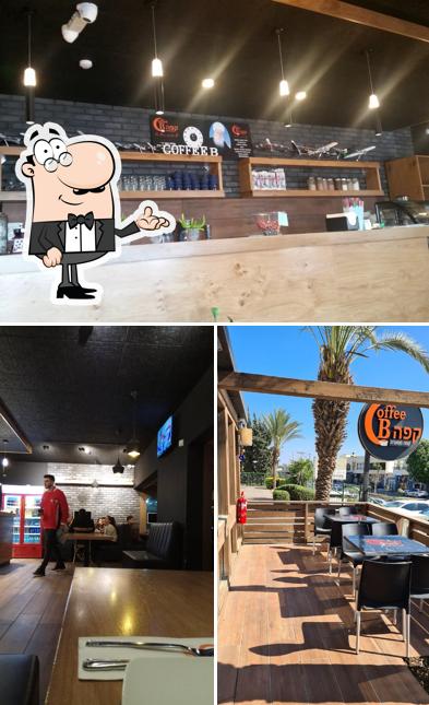 מרפסת העץ של Coffee B בין הדקלים, עם השלט הכתום